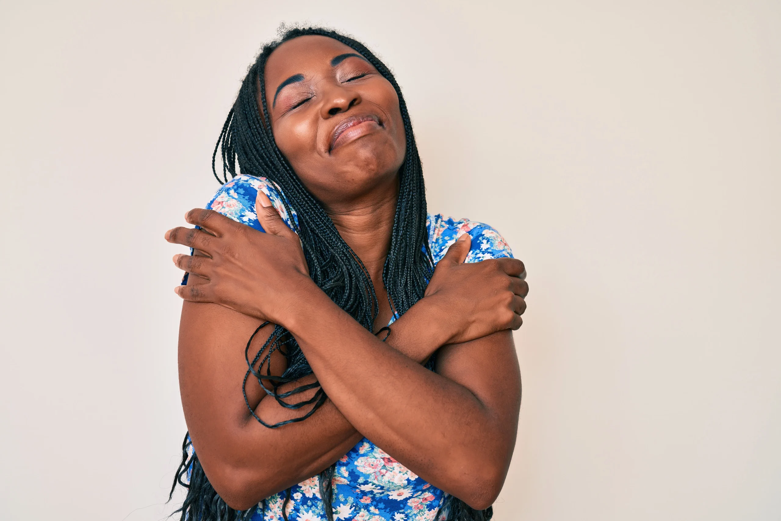 Woman smiling with eyes closed, hugging herself in a gesture of self-love.
