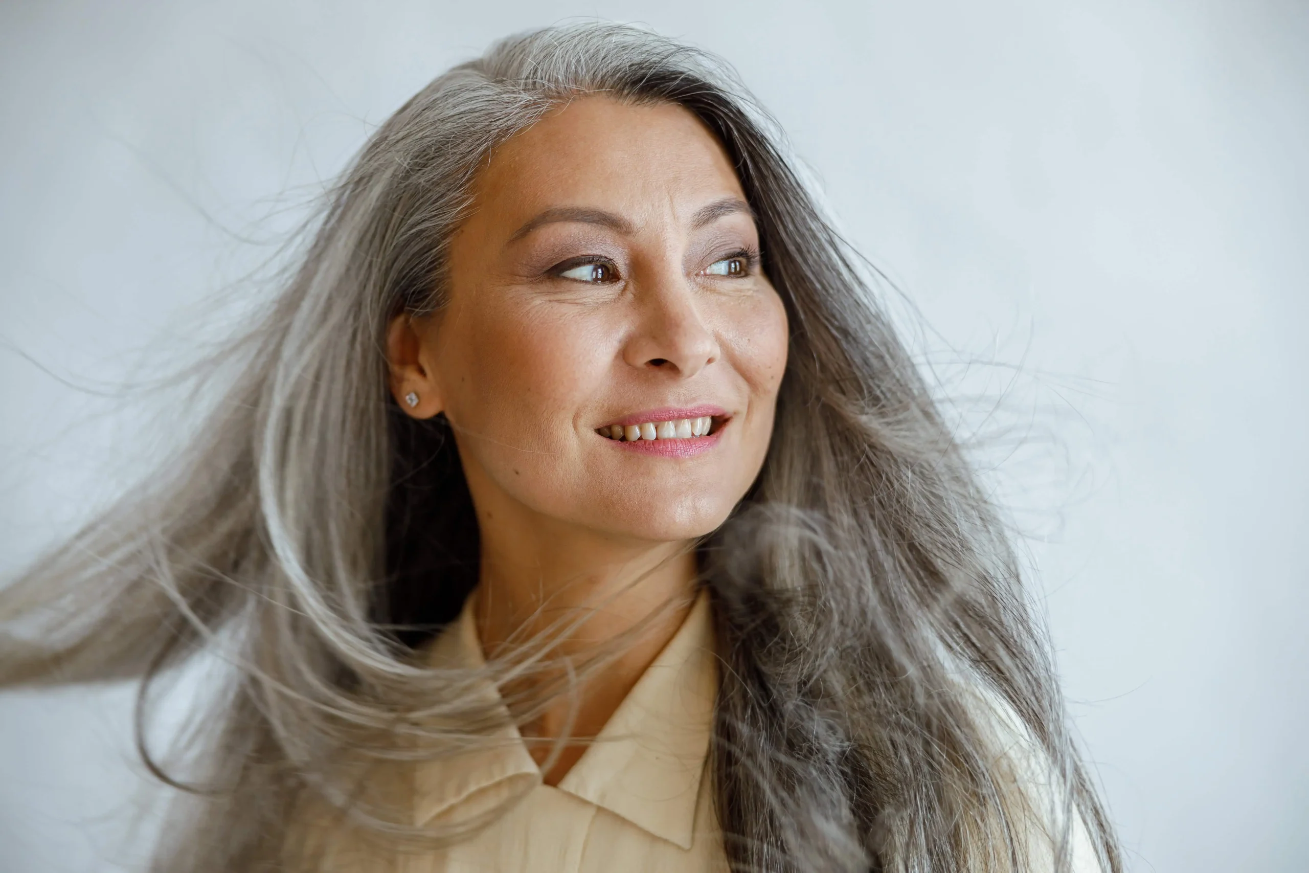 Smiling woman with long gray hair looking to the side with confidence.